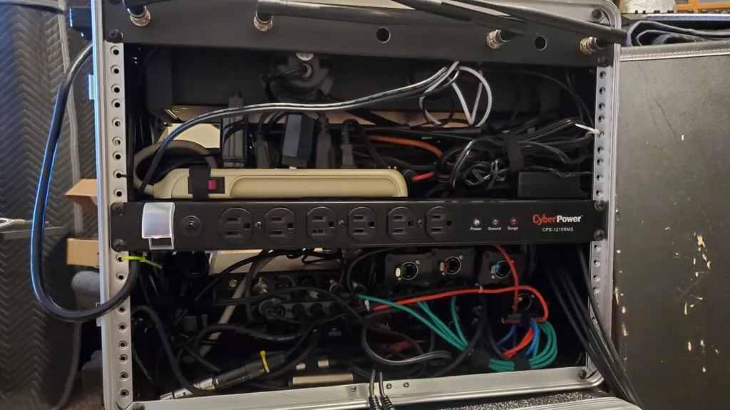 Inside our audio rack: a rack power strip with bundles of power and audio cables around it.