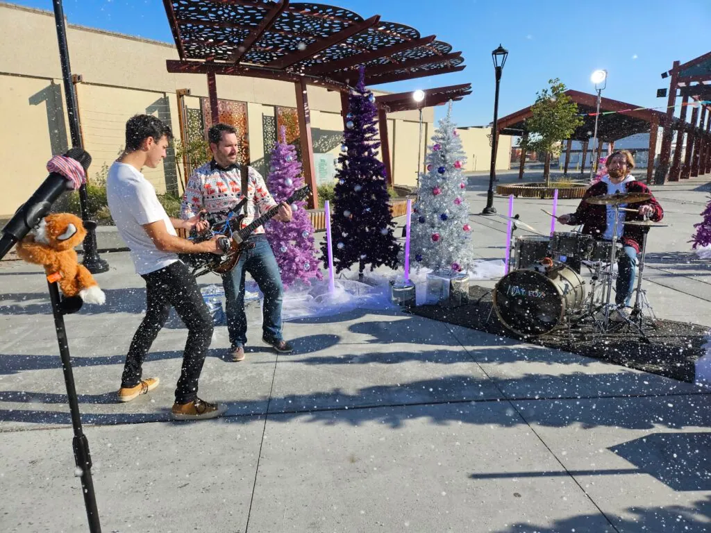 Fake snow falling as a camera operator films our guitar player up close, a stuffed fox hugging the mic stand.