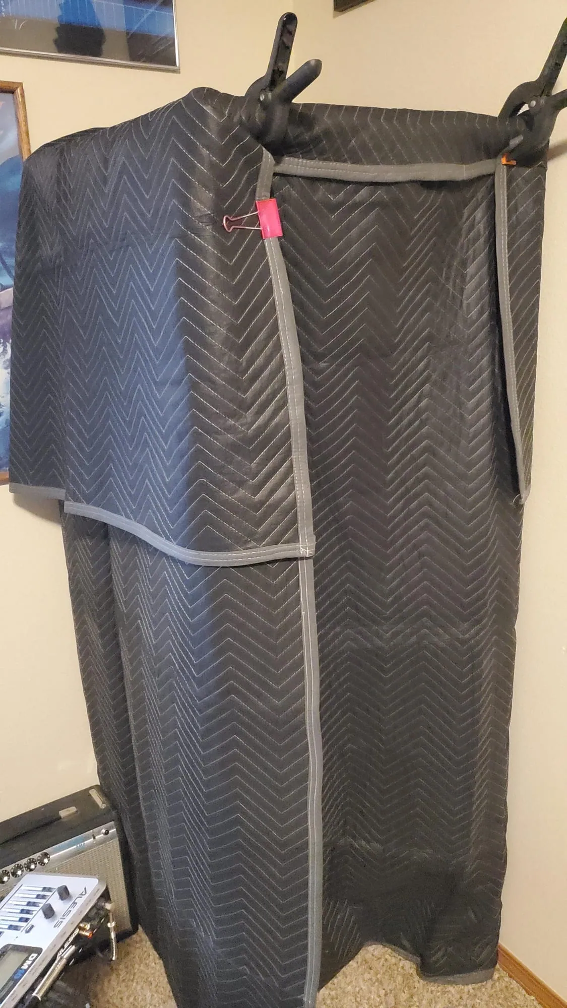 The booth closed up, draped in dark gray quilted moving blankets held on with big spring clamps.