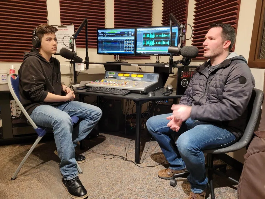 The student host listening at the broadcast desk as one of us talks into the mic.