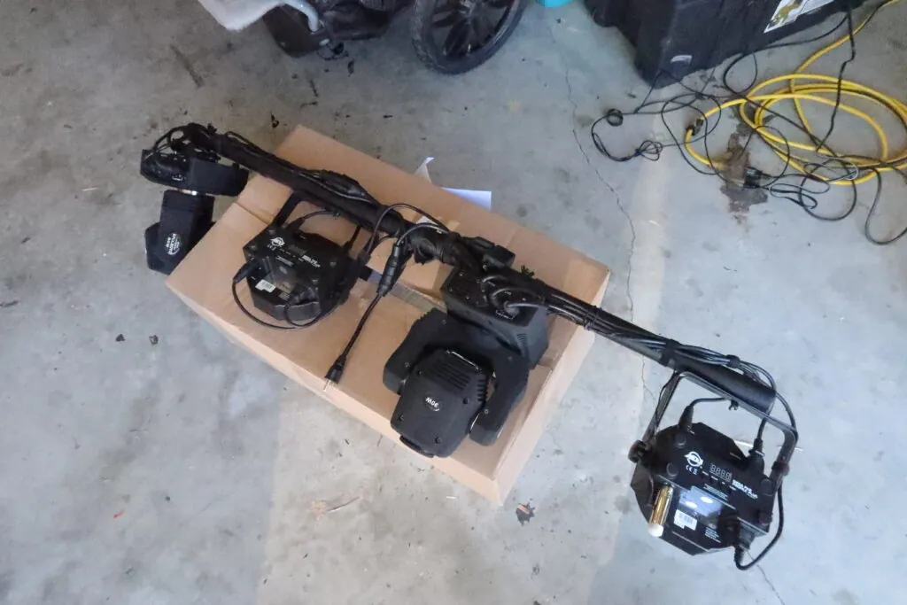 Our lighting bar laid out on a box in the garage, its stage lights and cables strapped along it.