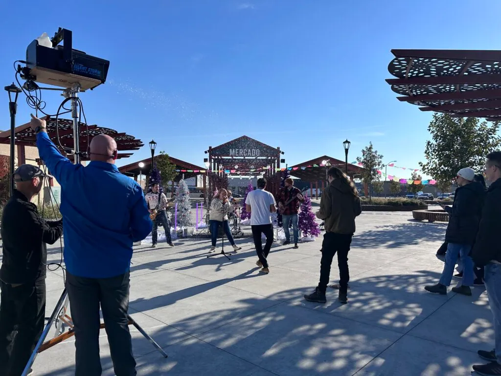 A crew member works the snow machine as we play among purple Christmas trees in front of the Mercado sign at Peanuts Park.