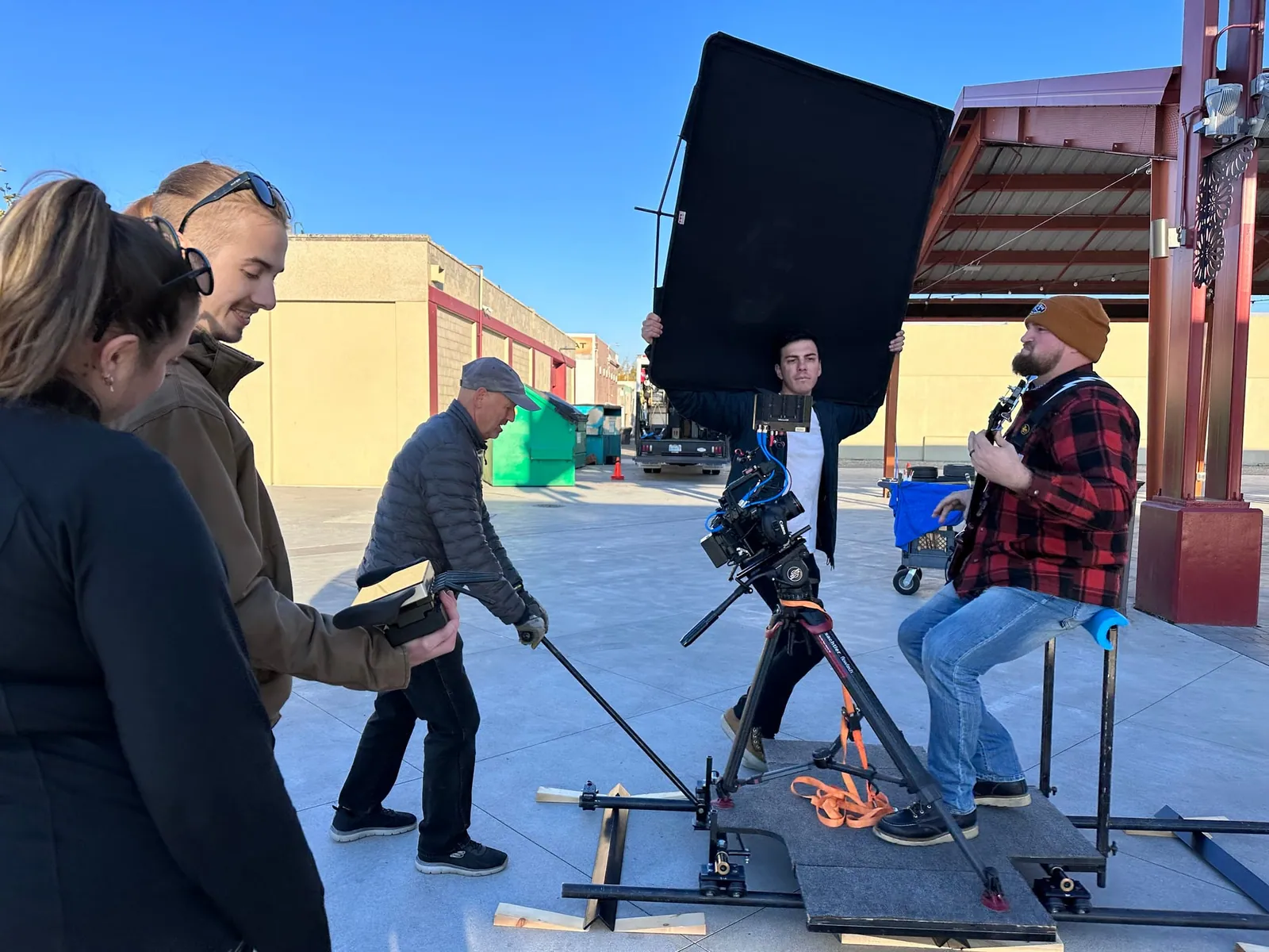 Our bass player filmed from a camera dolly as the crew holds up a black panel and two people check a handheld monitor.