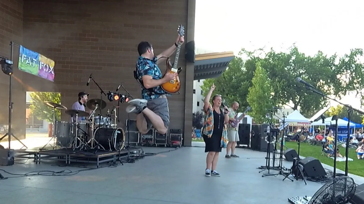 Our guitarist leaping high in the air on an outdoor stage, our singer pointing to the sky