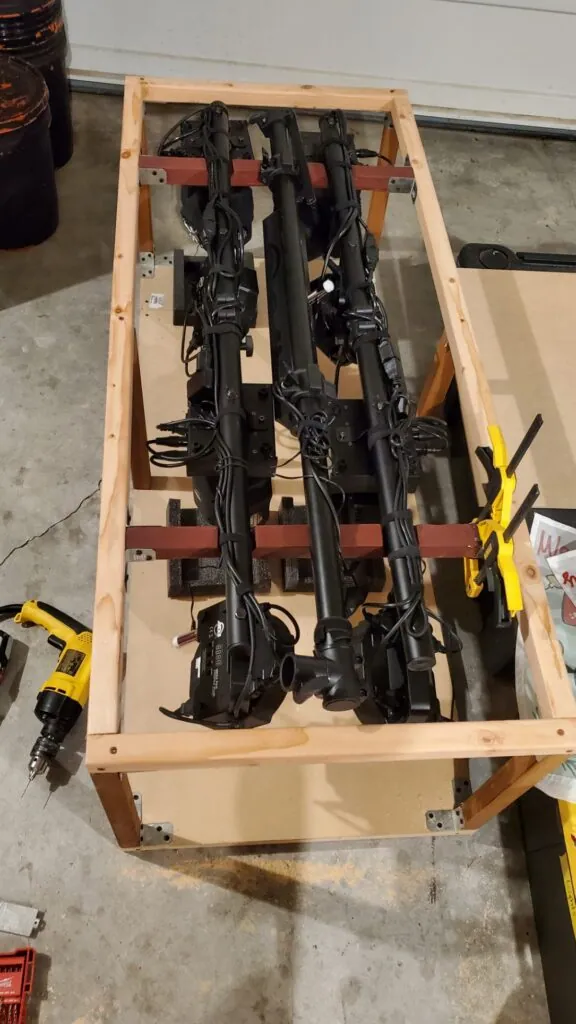 Our lighting rig laid in the bare wooden frame of the crate we built, a drill on the garage floor nearby.