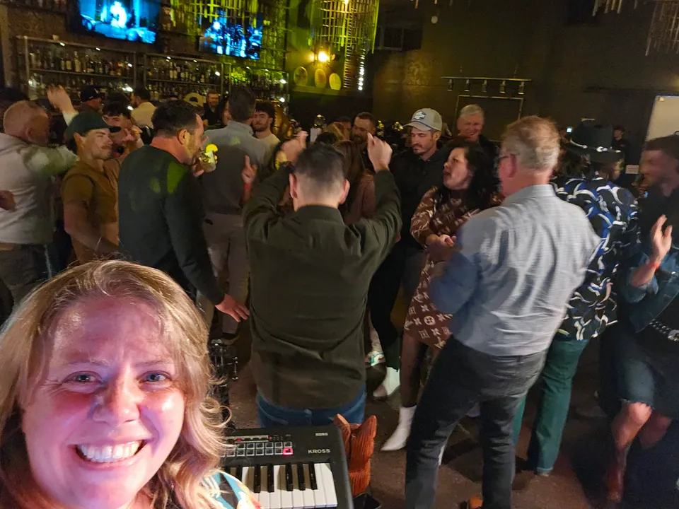 Our singer's selfie from behind her keyboard, a crowd dancing behind her